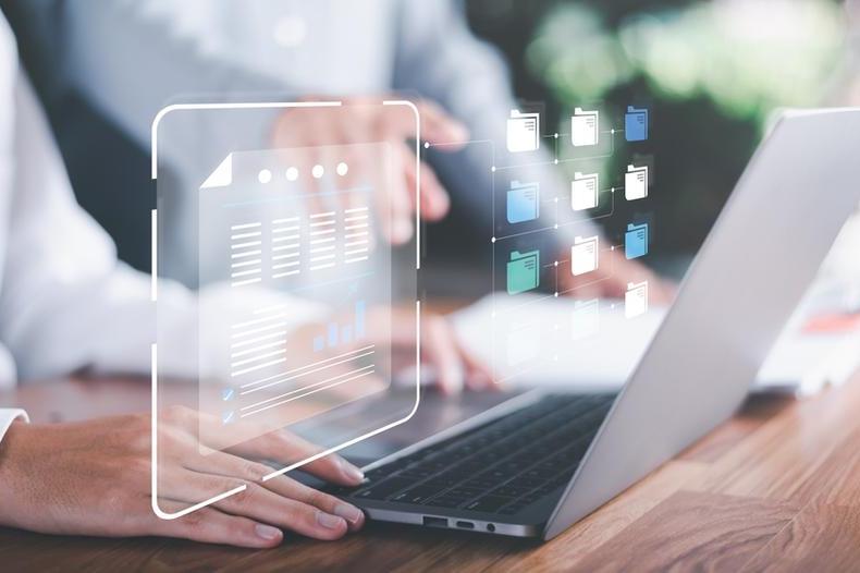 Person using a laptop with files popping our of the screen